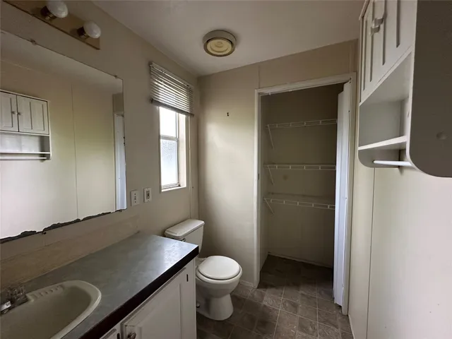 a bathroom with a granite countertop toilet sink and mirror