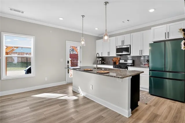 a kitchen with kitchen island granite countertop a sink a counter space stainless steel appliances and cabinets