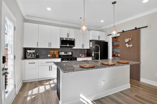 a kitchen with kitchen island granite countertop stainless steel appliances a stove a sink a refrigerator a center island and cabinets