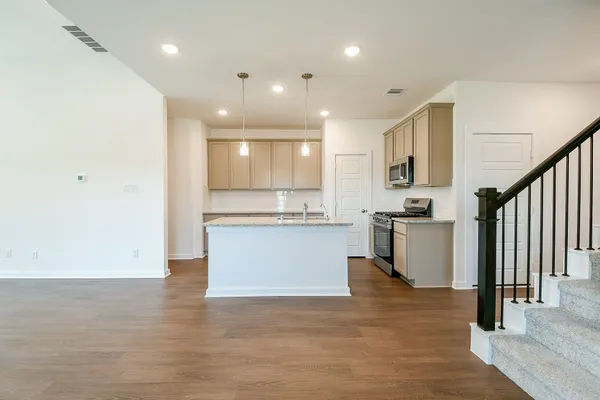 a view of kitchen with stainless steel appliances granite countertop a stove top oven a sink and a refrigerator