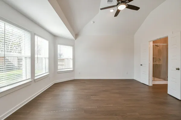 an empty room with wooden floor chandelier fan and windows