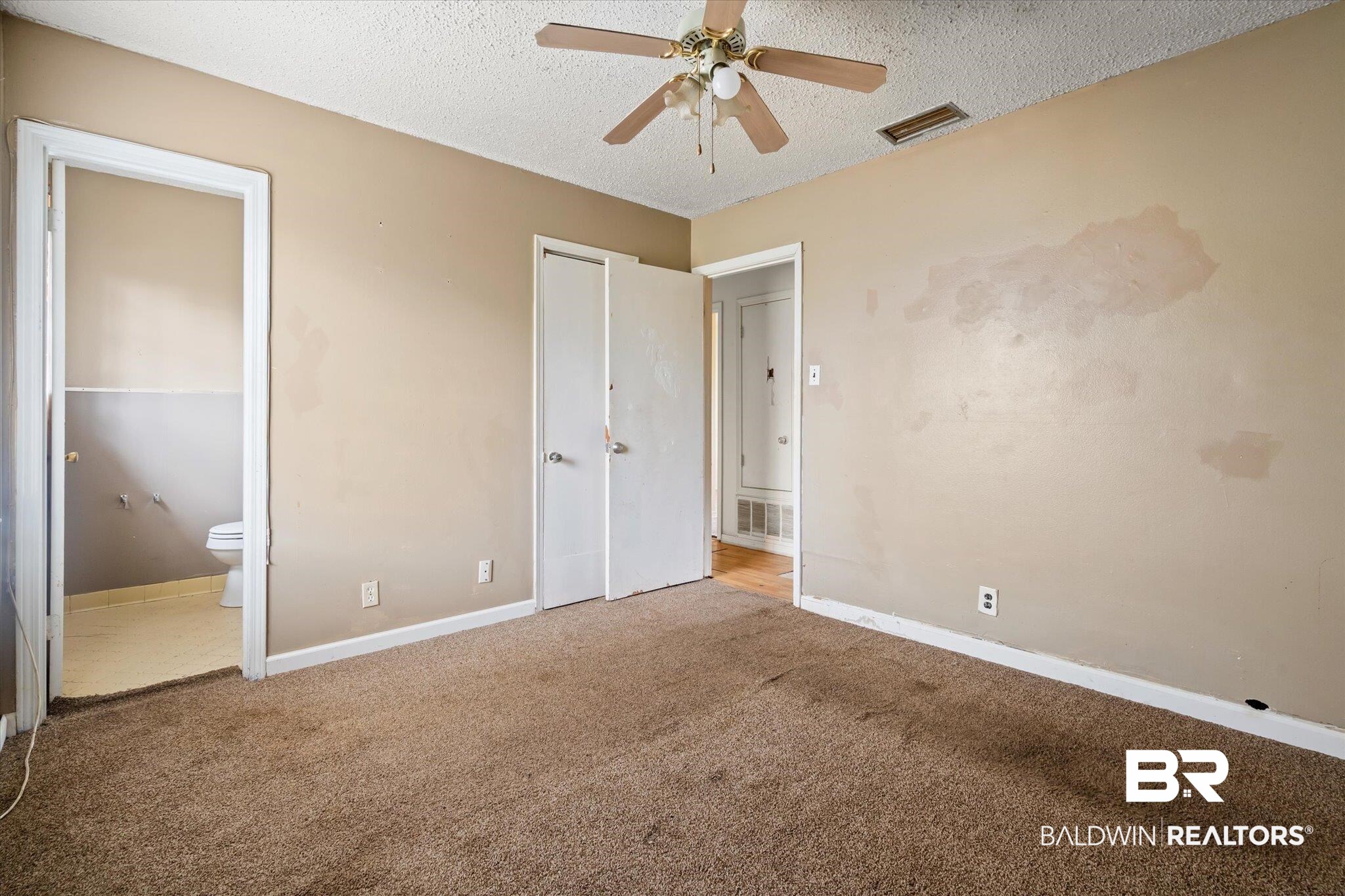 313 West 4th Avenue Foley, AL 36535 - Photo 10 of 20 Unfurnished bedroom with ceiling fan, ensuite bathroom, carpet floors, and a textured ceiling
