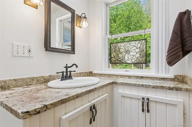 a bathroom with a granite countertop sink and a mirror