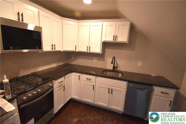 a kitchen with stainless steel appliances a sink dishwasher stove microwave and cabinets
