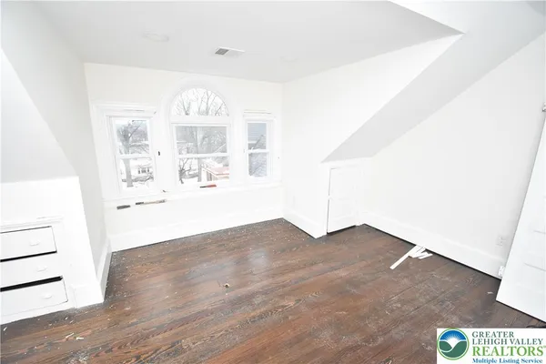 a view of a hallway with wooden floor and windows