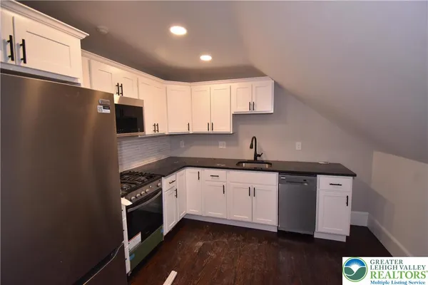 a kitchen with stainless steel appliances a sink a stove a microwave and cabinets
