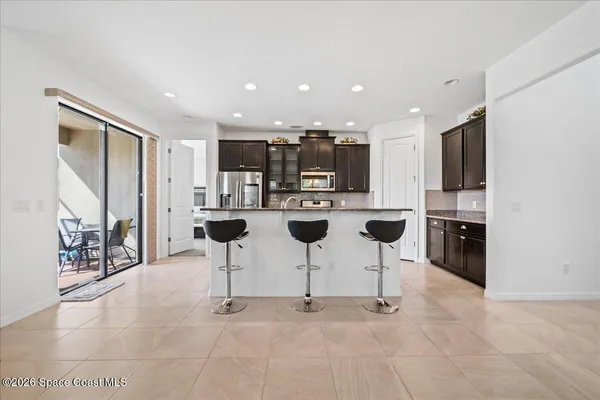 a kitchen with stainless steel appliances kitchen island granite countertop a refrigerator and chairs