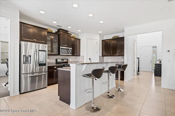 a kitchen with stainless steel appliances kitchen island granite countertop a refrigerator and a stove top oven