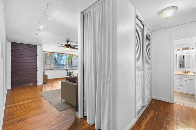 a walk in closet with wooden floor and a bathroom