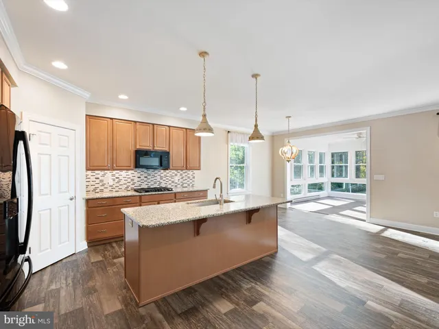 a large kitchen with kitchen island a large counter top space a sink stainless steel appliances and cabinets