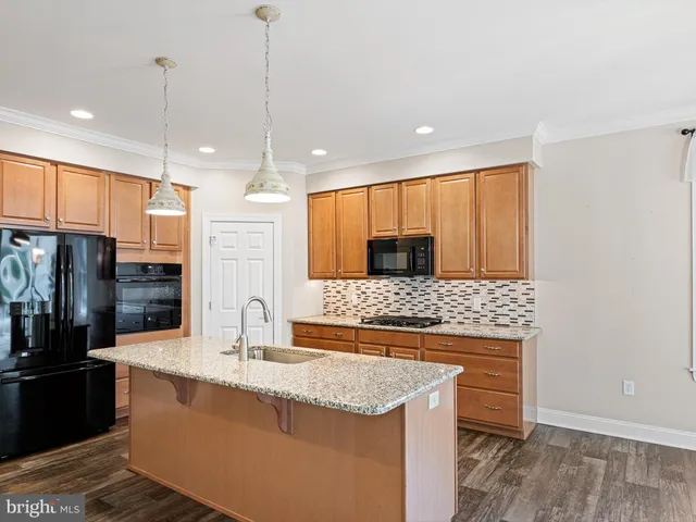 a kitchen with stainless steel appliances granite countertop wooden cabinets and a refrigerator