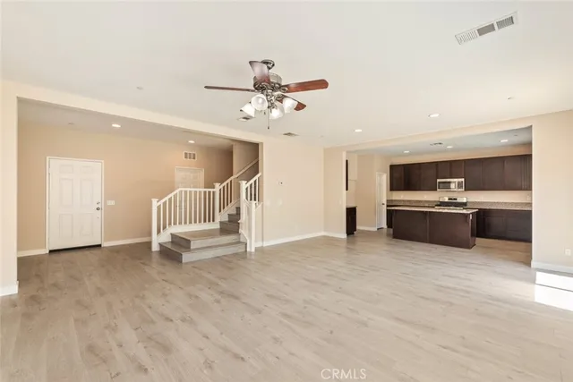 a large kitchen with a large counter top a sink stainless steel appliances and cabinets