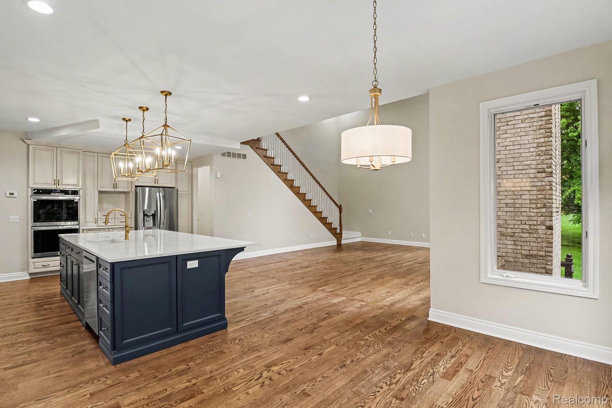 4875 Green Meadow Lane Rochester, MI 48306 - Photo 13 of 60 Kitchen island with a light-toned countertop, built-in appliances, and a gold-toned faucet