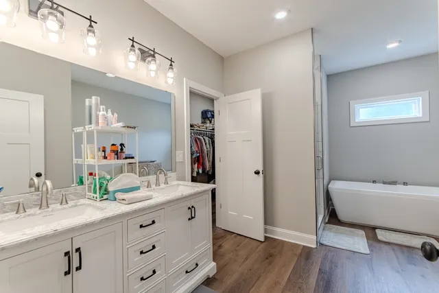 a bathroom with a double vanity sink a mirror and a bathtub