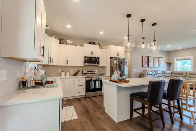 a kitchen with stainless steel appliances kitchen island granite countertop a table chairs and a cabinets