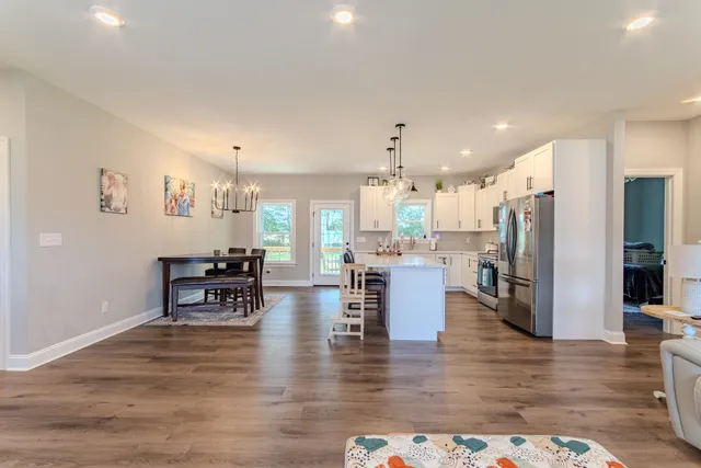 a dining room with furniture wooden floor and a kitchen view
