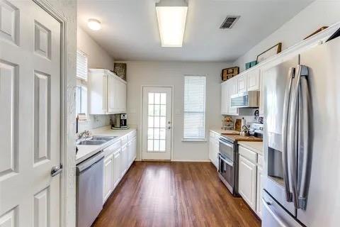 125 Timber Cross Court Azle, TX 76020 - Photo 2 of 17 a kitchen with granite countertop a refrigerator a sink dishwasher a stove and white cabinets with wooden floor