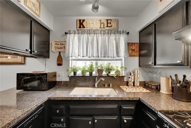 a kitchen with granite countertop stainless steel appliances a sink a stove and a counter space