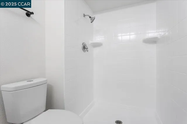 a white toilet sitting next to a shower
