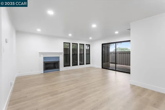 a view of an empty room with wooden floor and fireplace