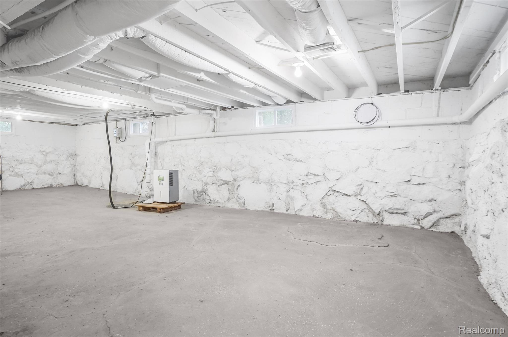 8330 Baldwin Road Gaines, MI 48436 - Photo 21 of 27 Concrete flooring with painted stone foundation walls and exposed white ceiling beams