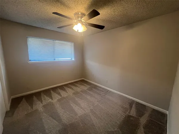 an empty room with a chandelier fan and windows
