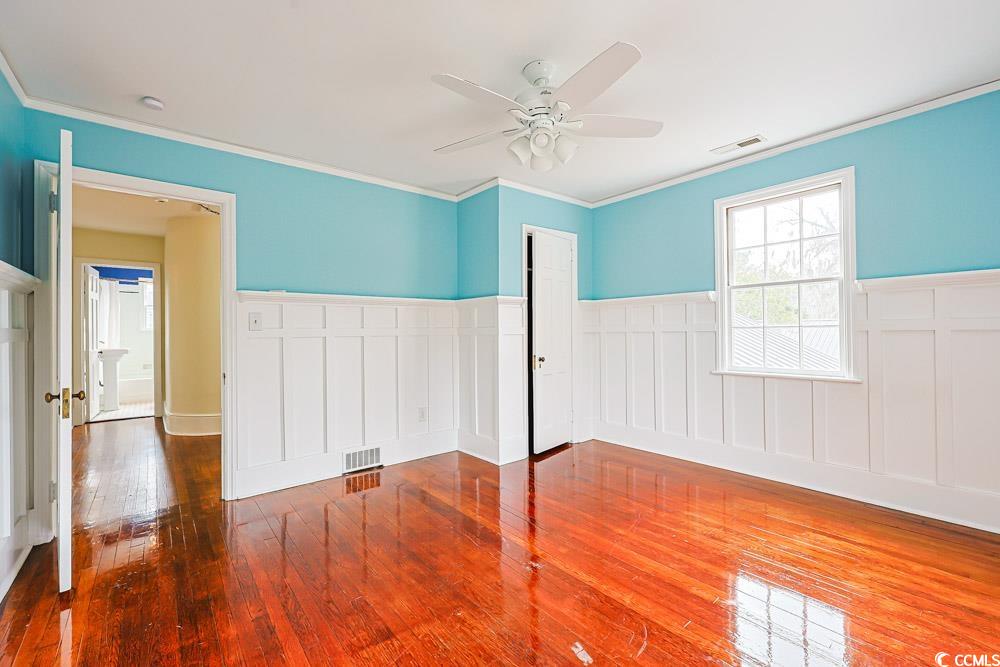 509 Beaty Street Conway, SC 29526 - Photo 20 of 40 Unfurnished room featuring wood-type flooring, crown molding, a wainscoted wall, and ceiling fan