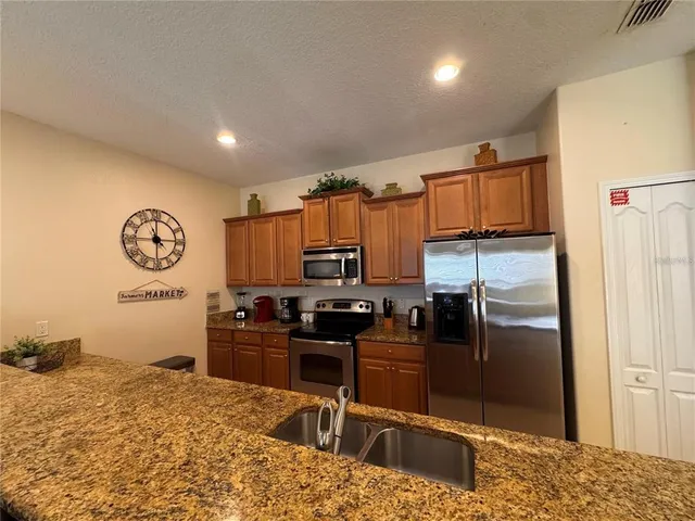 a kitchen with stainless steel appliances granite countertop a refrigerator a stove a sink and a counter space