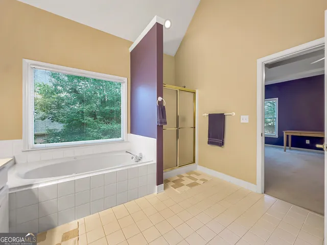 a bathroom with a tub a sink double vanity and a large mirror