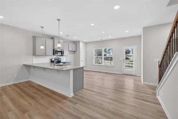 a kitchen with stainless steel appliances granite countertop a refrigerator a sink dishwasher a stove and a wooden floor