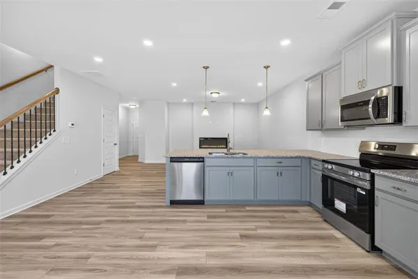 a large kitchen with stainless steel appliances kitchen island granite countertop a large stove a sink dishwasher and a microwave oven with large wooden cabinets