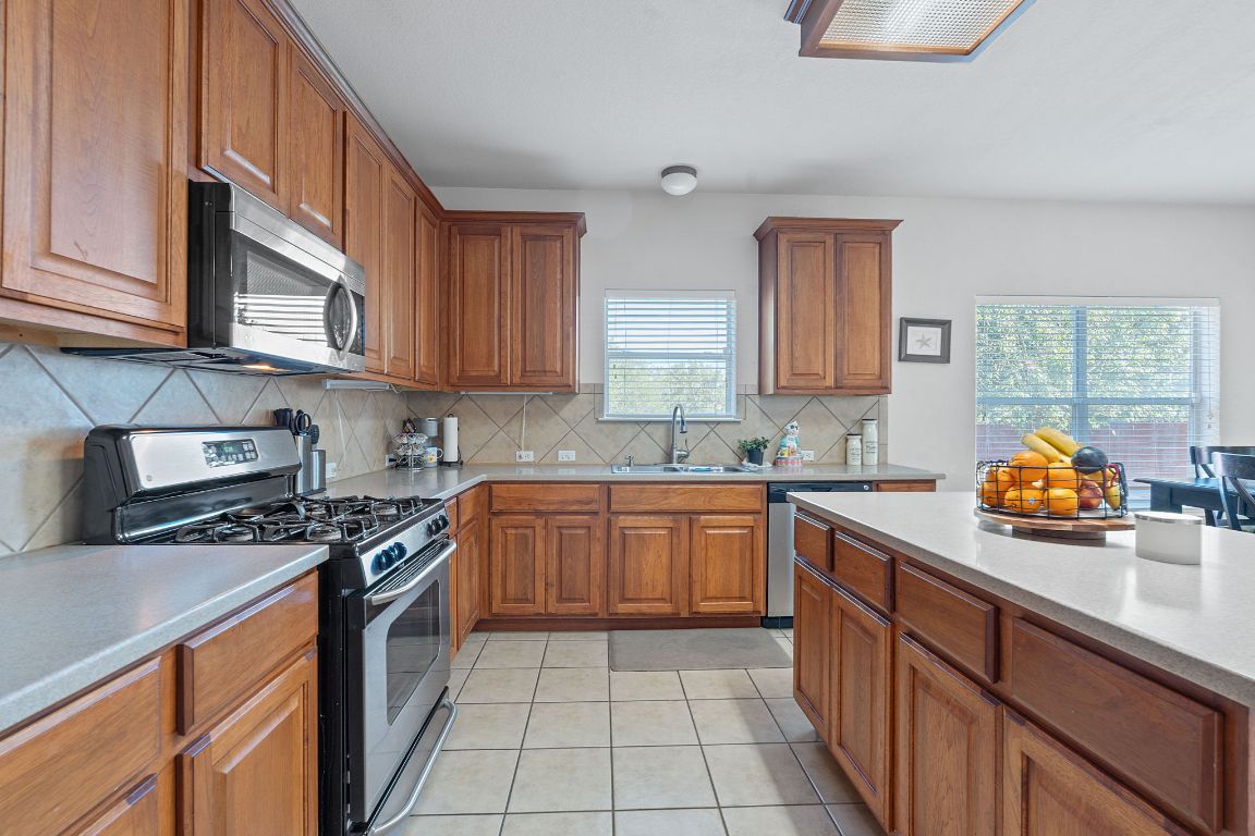1024 Portchester Castle Path Pflugerville, TX 78660 - Photo 11 of 40 Kitchen with stainless steel appliances, brown cabinets, and light tile patterned floors