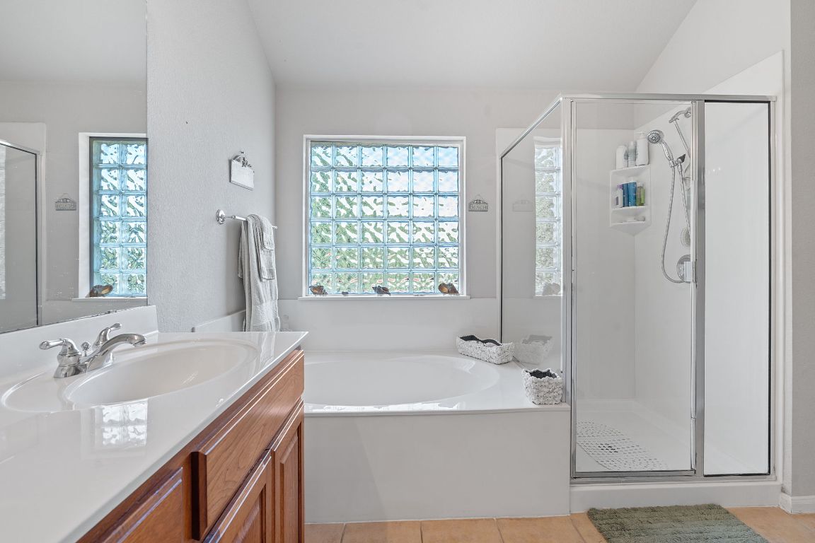 1024 Portchester Castle Path Pflugerville, TX 78660 - Photo 18 of 40 Full bathroom with vanity, a stall shower, a bath, light tile patterned floors, and healthy amount of natural light