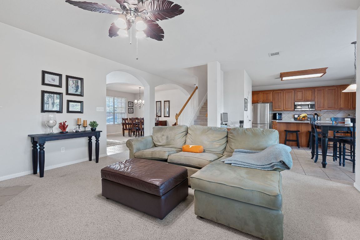 1024 Portchester Castle Path Pflugerville, TX 78660 - Photo 4 of 40 Living room with arched walkways, light carpet, light tile patterned floors, ceiling fan, and a chandelier