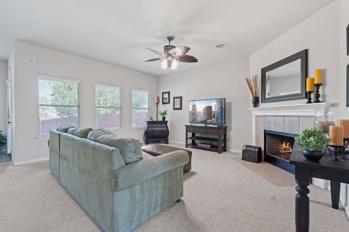 1024 Portchester Castle Path Pflugerville, TX 78660 - Photo 6 of 40 Living area with light colored carpet, a fireplace, and a ceiling fan