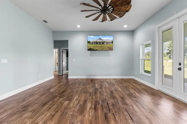 a view of an empty room and window with wooden floor