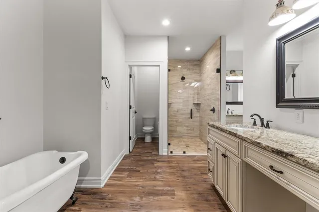 a bathroom with a granite countertop sink a mirror a bathtub and shower