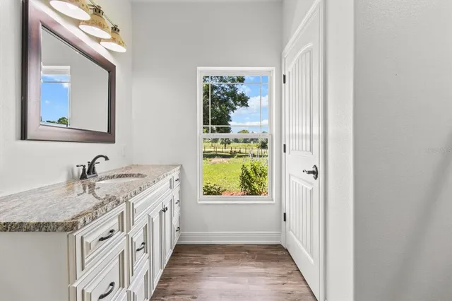a bathroom with a granite countertop sink and a window