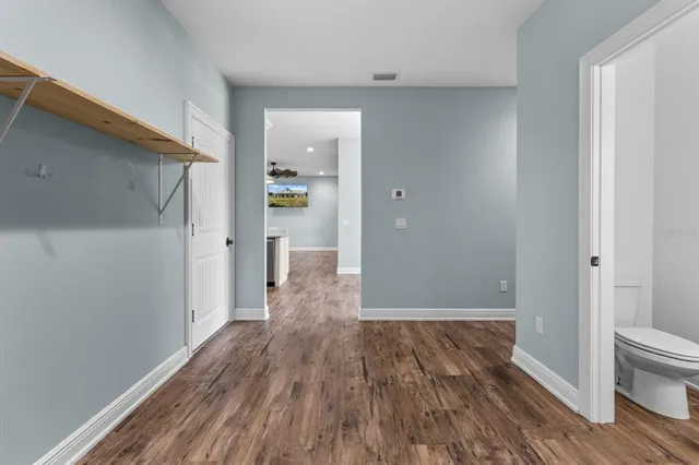 a view of a hallway with wooden floor and a bathroom