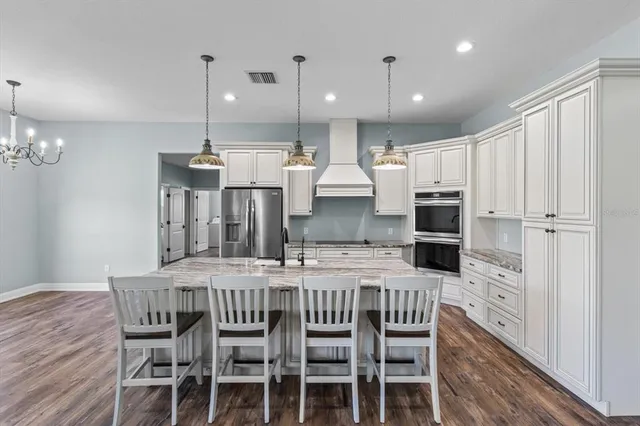 a kitchen with stainless steel appliances kitchen island granite countertop a table chairs and a refrigerator
