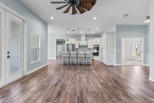 a living room with stainless steel appliances kitchen island hardwood floor and a view of kitchen