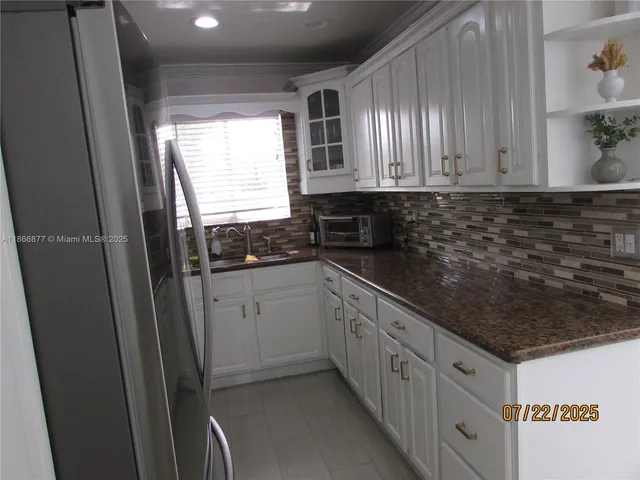 a kitchen with granite countertop a sink stove and cabinets