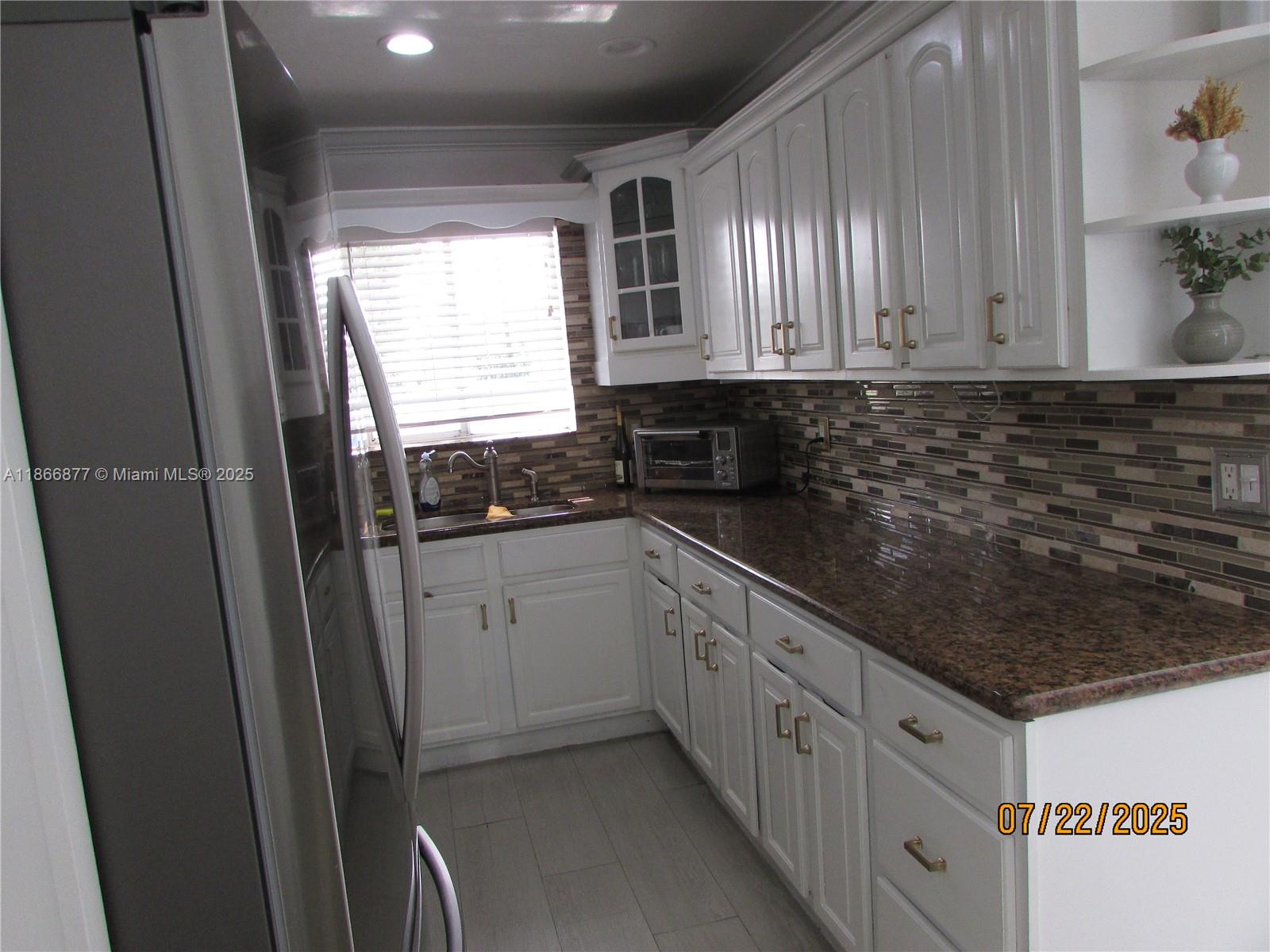 5620 Southwest 140th Place Miami, FL 33183 - Photo 8 of 12 a kitchen with granite countertop a sink stove and cabinets
