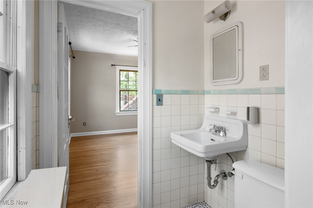 3677 Traver Road Shaker Heights, OH 44122 - Photo 21 of 35 Bathroom with tile walls, toilet, wainscoting, wood finished floors, and a sink
