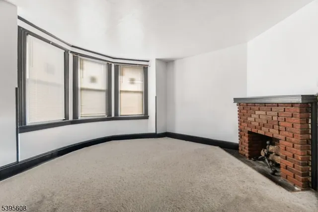a view of an empty room with a fireplace and a window