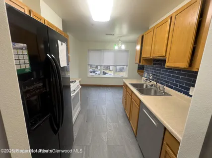 a kitchen with a refrigerator a sink and wooden cabinets