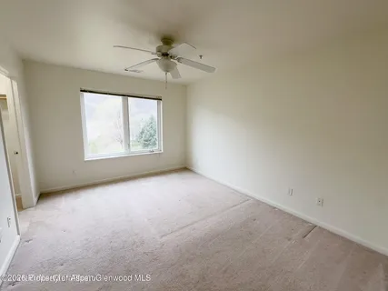 an empty room with windows and fan