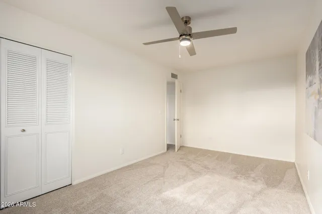 an empty room with a ceiling fan and a window