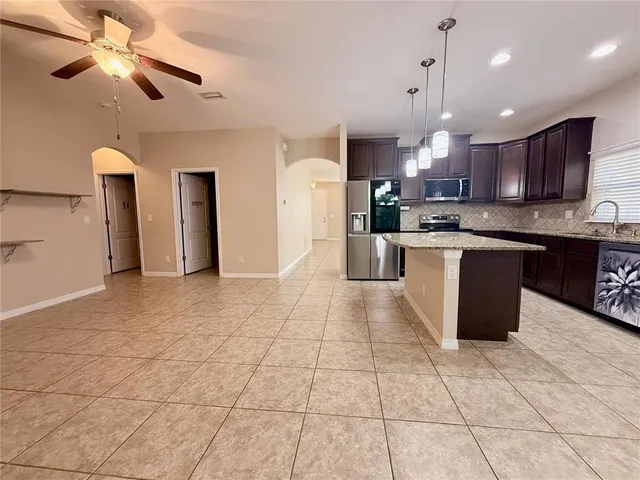 a large kitchen with granite countertop a large counter top space appliances and cabinets