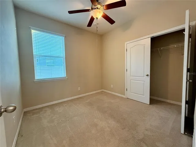 an empty room with chandelier fan and windows